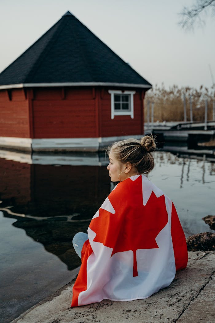 The Art of Drawing Readers In: Your attractive post title goes here A contemplative young woman sits by the water wrapped in a Canadian flag in Toronto.